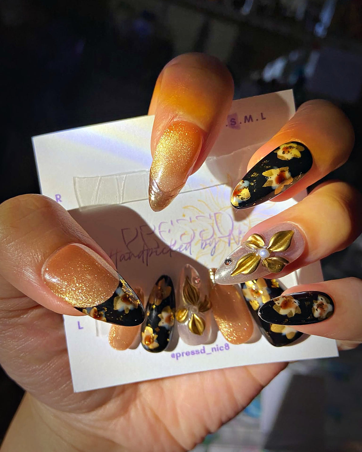 Amber Garden press-on nails: black almond nails with hand-painted amber flowers and gold leaf